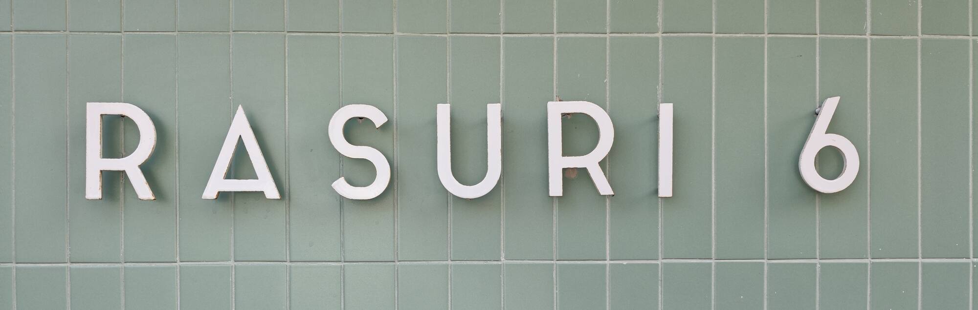 Inscripția RASURI 6 pe faianța verde de la intrare